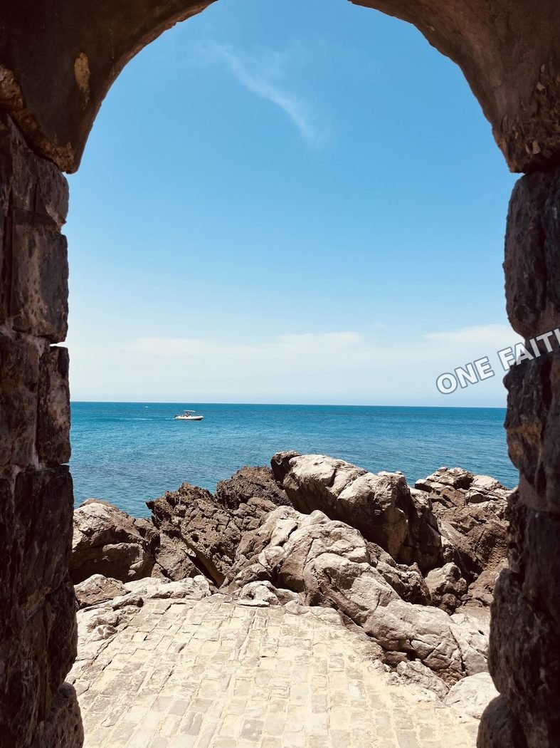 A view of the sea through a stone archway.